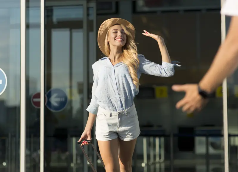 Young girl coming out of the airport terminal and waving