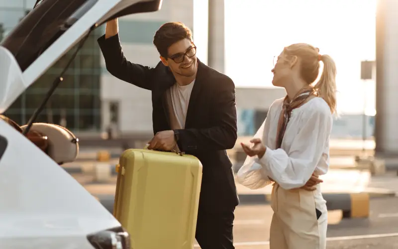 Young couple packing their suitcases in the rental car