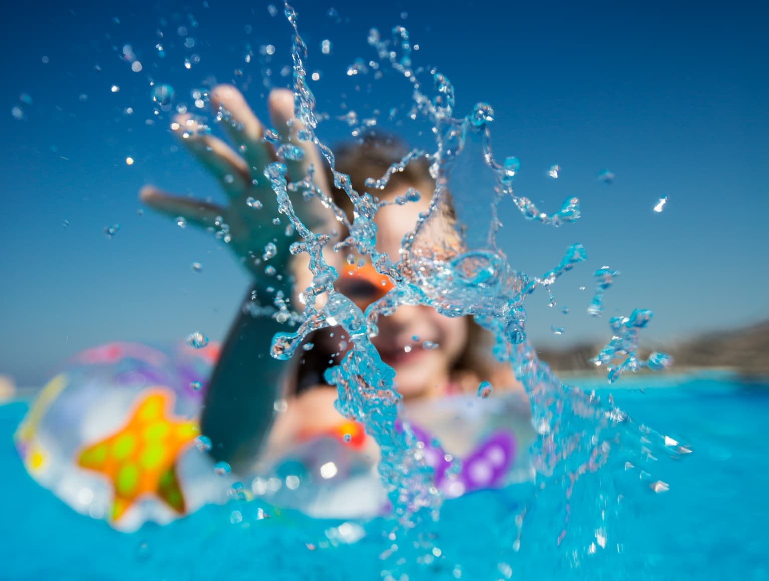 Girl playing with water in a swimming pool