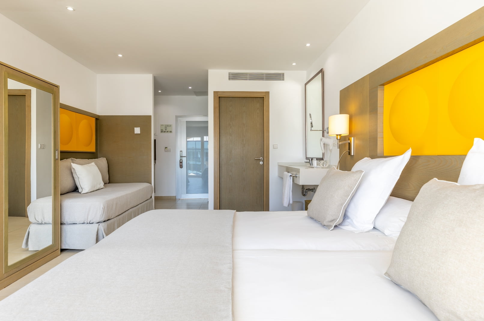 Zona de descanso en colores blanco y arena, con lavabo abierto a la habitación Estudio 5